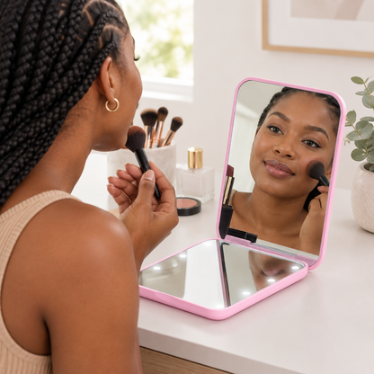 Woman using the pink mirror while applying makeup